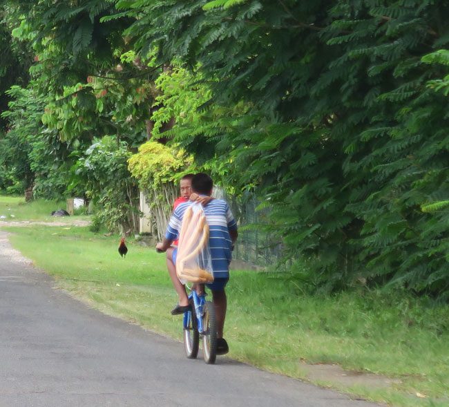 Tahitians with baguette on bike in Moorea French Polynesia