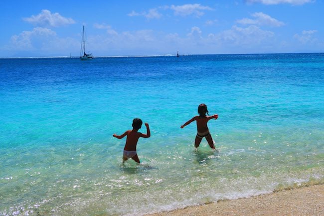 children tossing rocks Fare beach Huahine Island French Polynesia