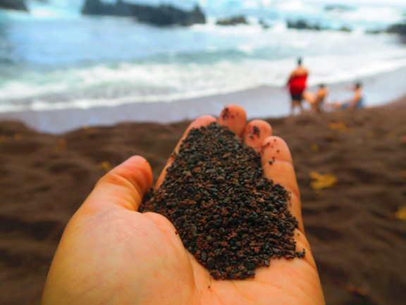 Holding soil in Kaihalulu Red Sand Beach - road to Hana - Maui Hawaii