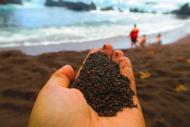 Holding soil in Kaihalulu Red Sand Beach - road to Hana - Maui Hawaii