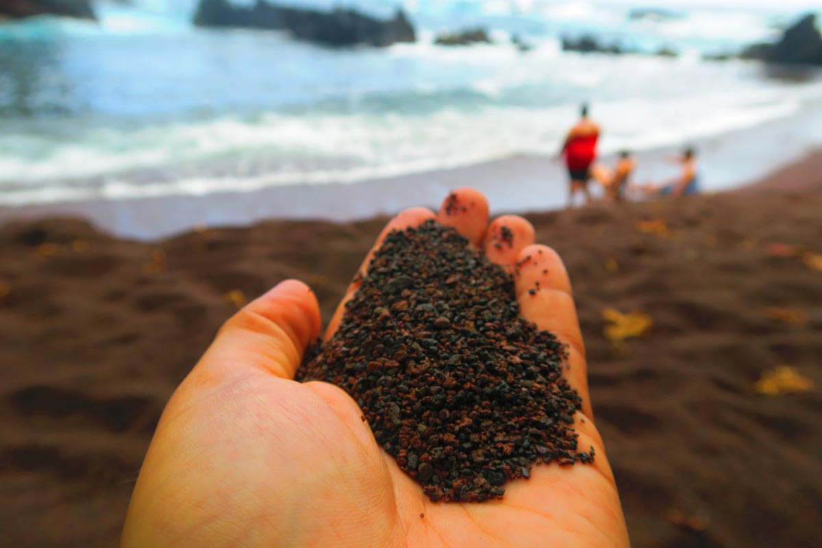 Holding soil in Kaihalulu Red Sand Beach - road to Hana - Maui Hawaii