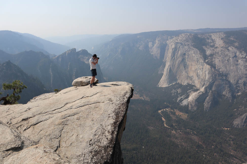 Hiker photographing yosemite valley from taft point trail
